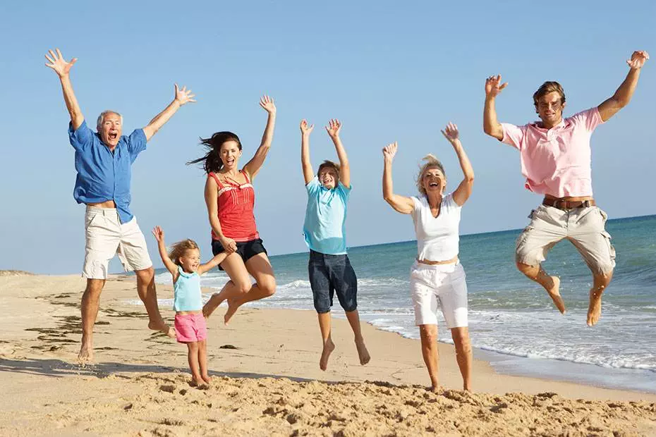 Family jumping happily on the beach; Healthy