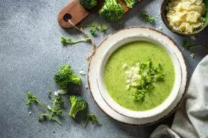 Broccoli soup with cheese garnish on textured background.