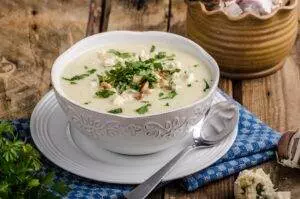 Creamy cauliflower soup garnished with herbs and nuts.