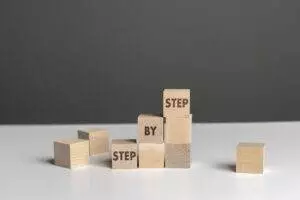 Wooden blocks spelling step by step on table.