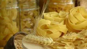 Uncooked pasta and wheat stalks in jars.