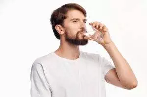 Man drinking water from glass for hydration.