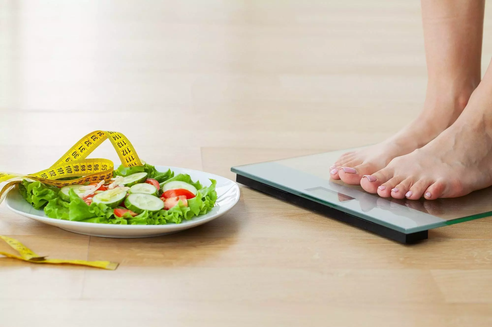 Healthy eating with salad and measuring tape.