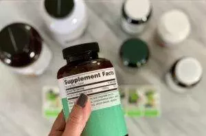 Holding a bottle of vitamin supplements, focus on label.