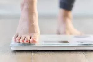 Person stepping onto a digital scale.