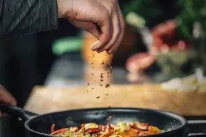 Chef seasoning stir-fry in pan