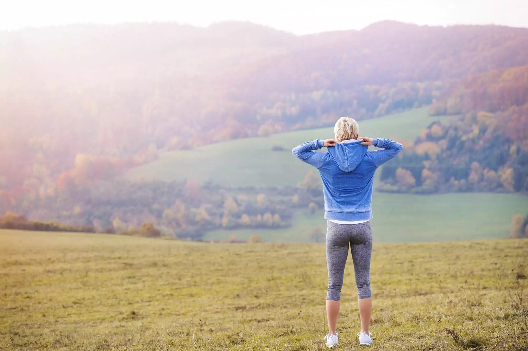 Woman enjoying scenic hillside view during golden hour; Balanced lifestyle