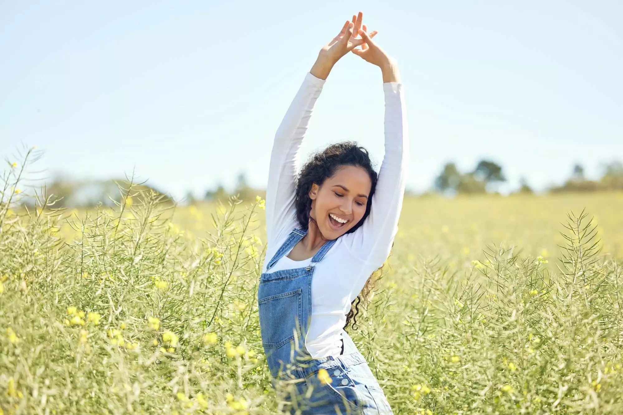 Joyful woman stretching in sunny flower field