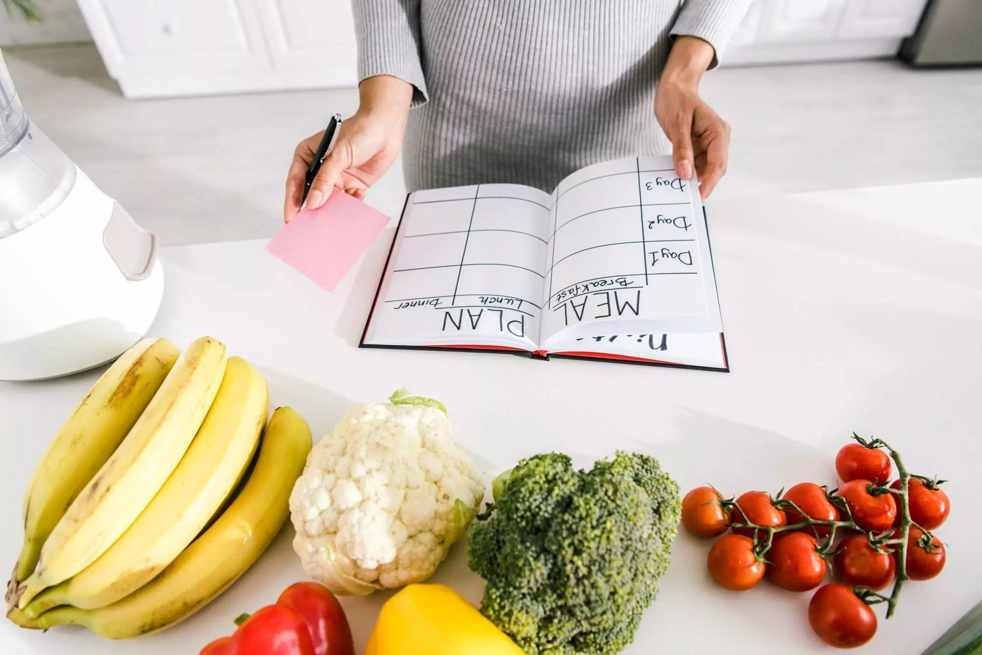 Person planning meals with fresh produce on table.