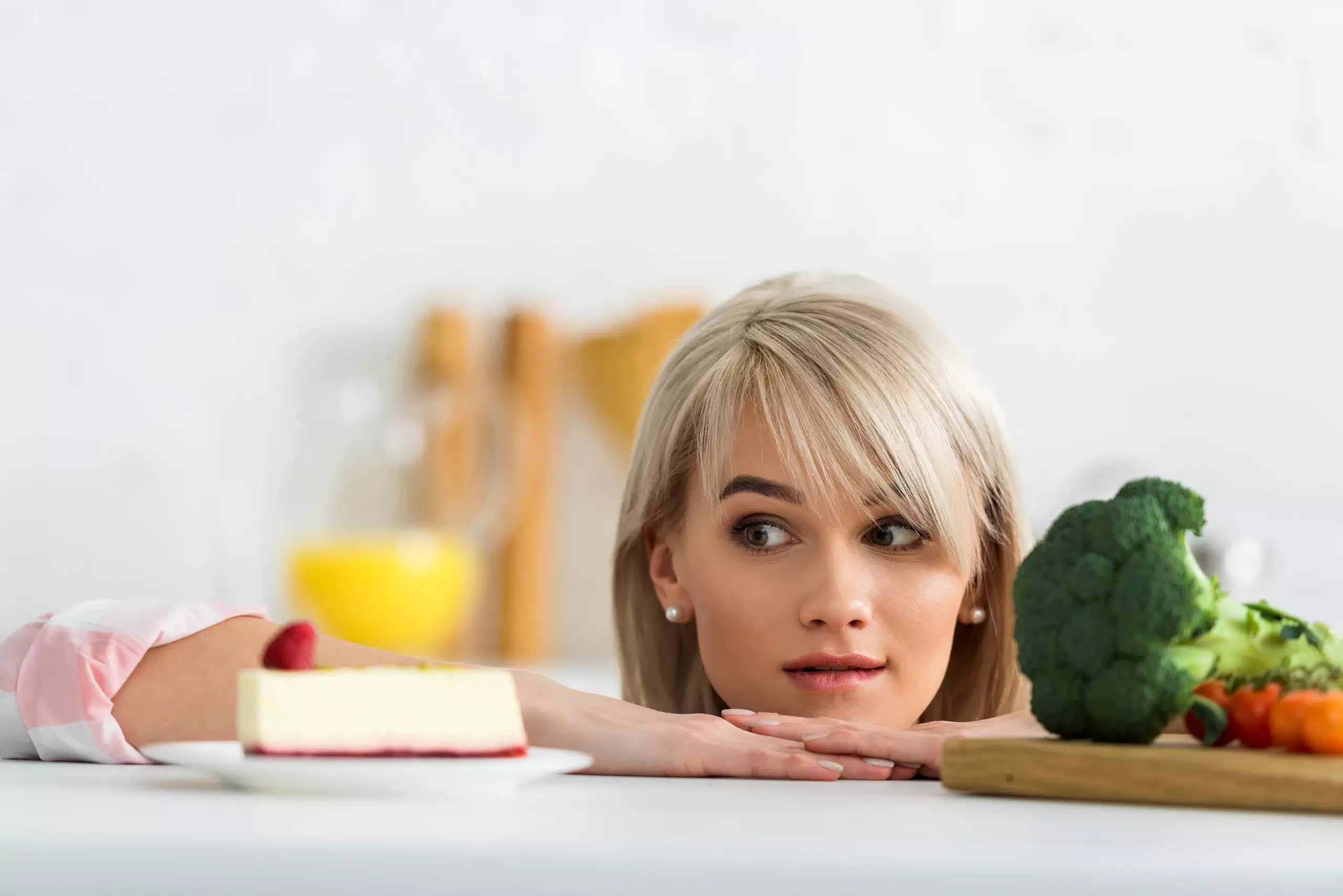 Woman choosing between cake and vegetables.