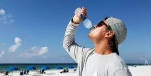 Dehydrated Man drinking water on sunny beach