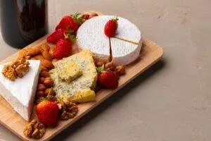 Cheese board with strawberries, almonds, and walnuts.