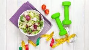Healthy salad, dumbbells, tape measure, fitness concept.