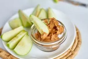 Apple slices with peanut butter on plate.