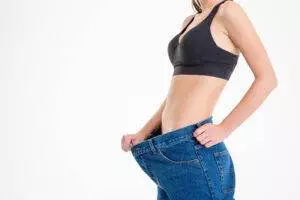 Woman showing weight loss wearing oversized jeans.