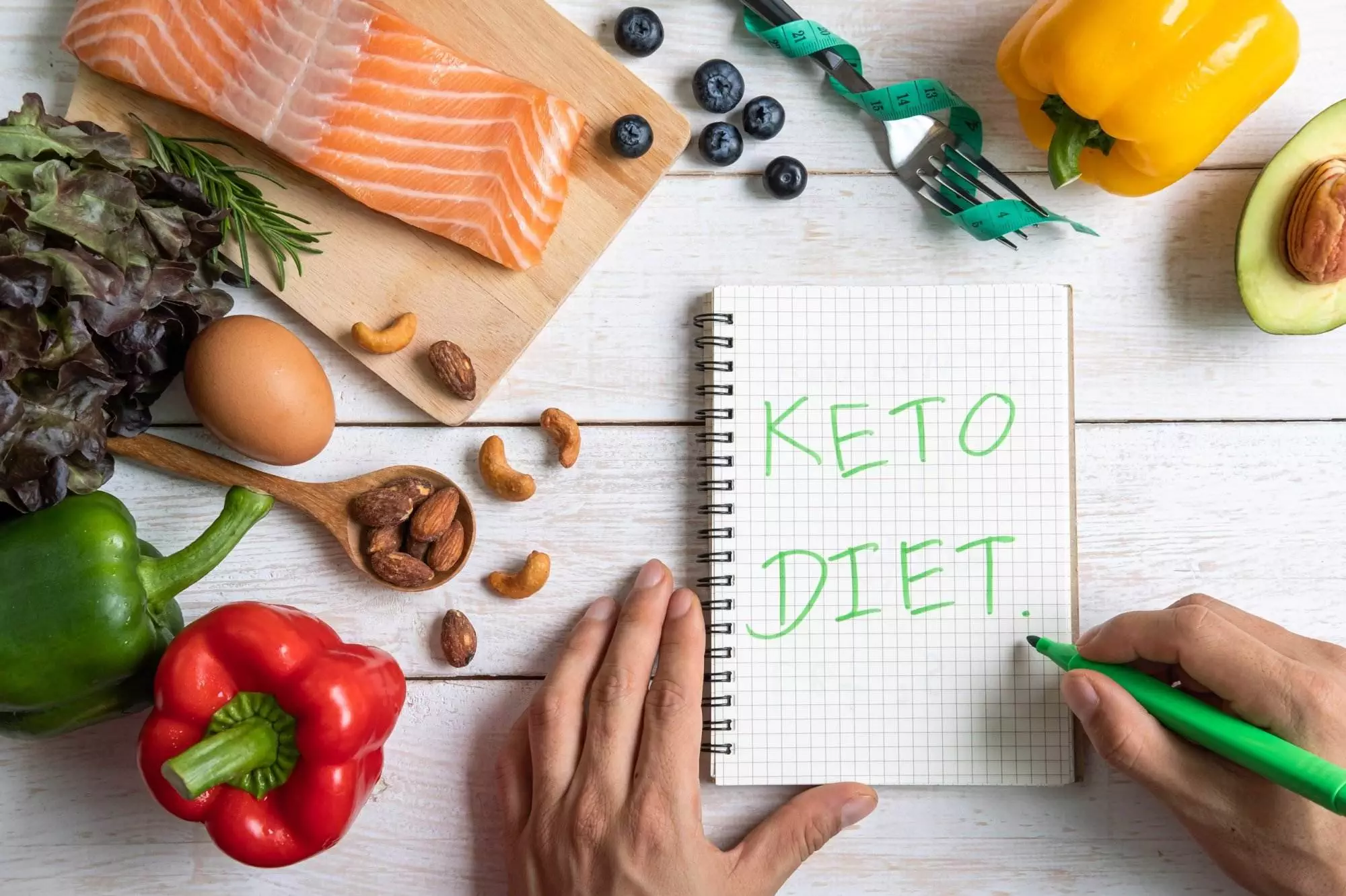 Keto diet planning with healthy foods and notebook.