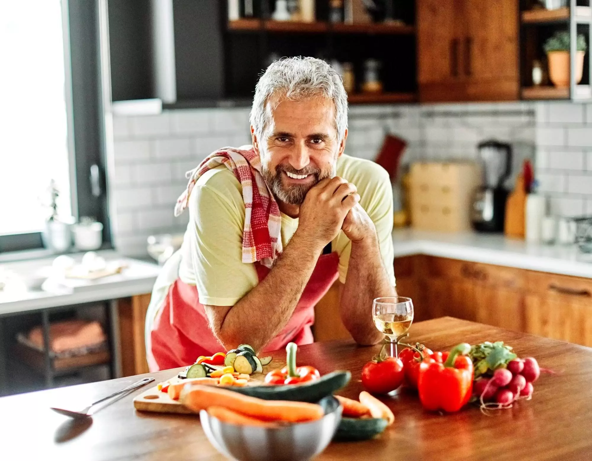Man smiling in kitchen with fresh vegetables
