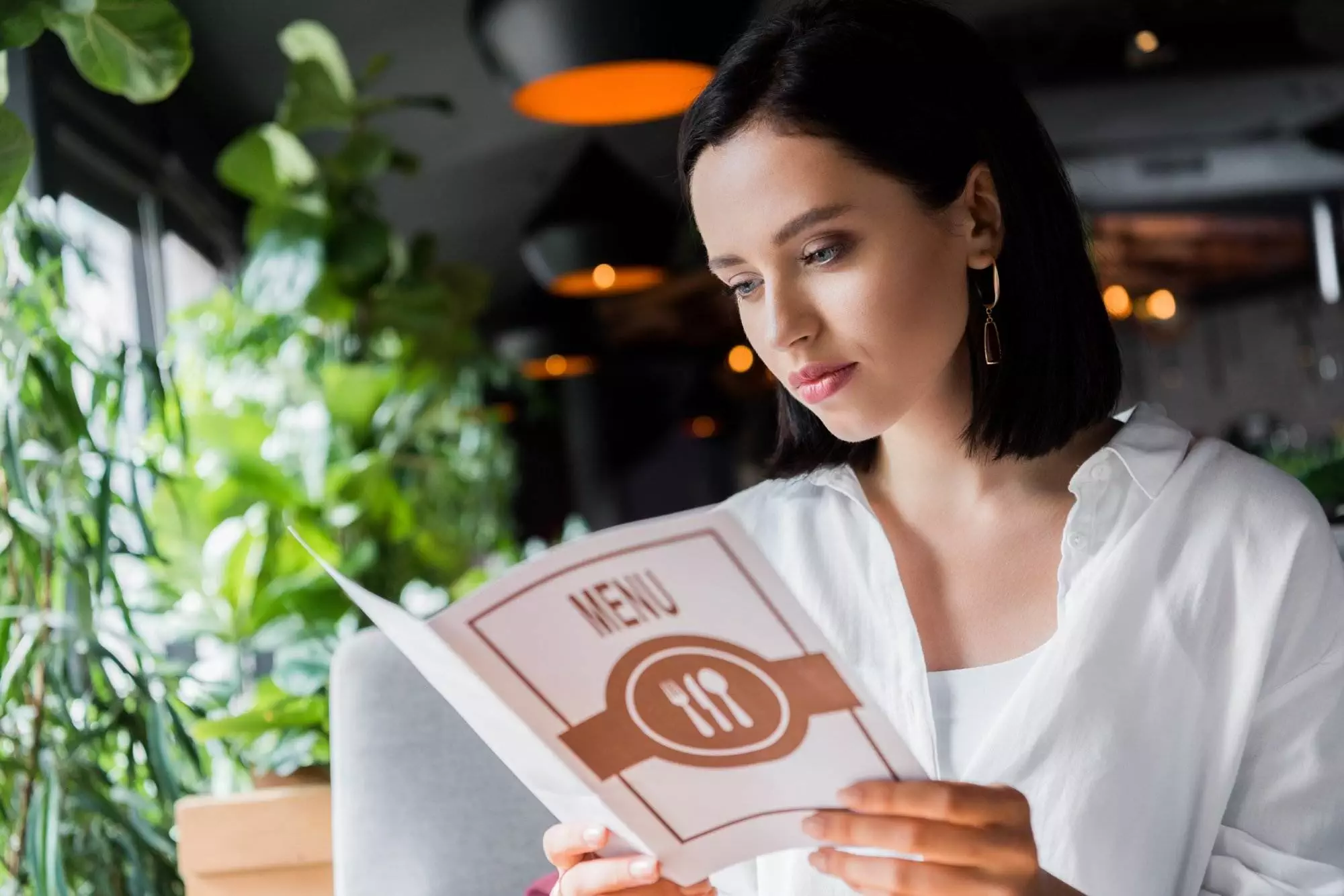 Woman reading menu at restaurant.