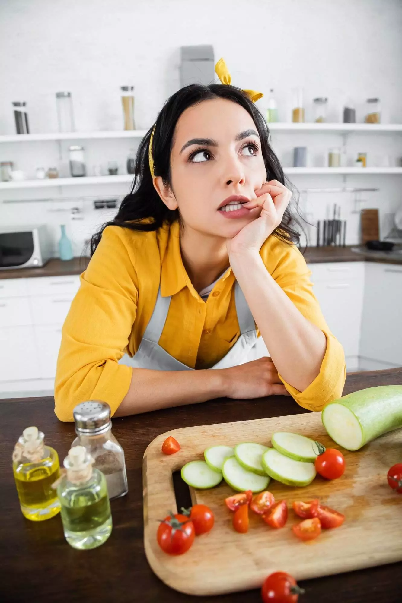 Woman contemplating while preparing vegetables in kitchen