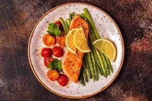 Grilled salmon, asparagus, tomatoes on plate.