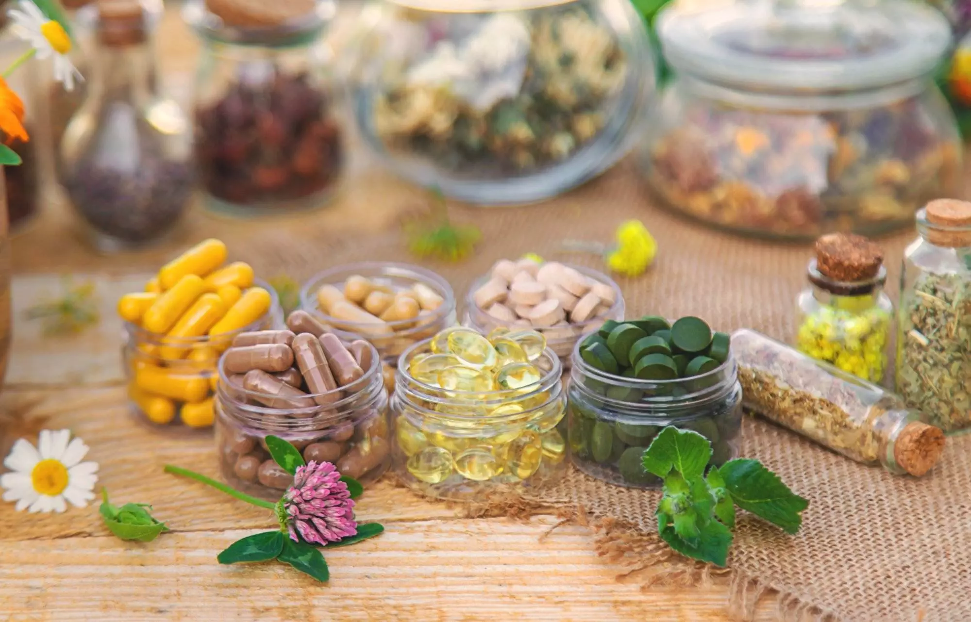 Herbal supplements and dried herbs on wooden table.