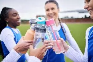 Athletes toasting with water bottles on sports field.