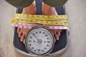 Feet on a weight scale with measuring tape around