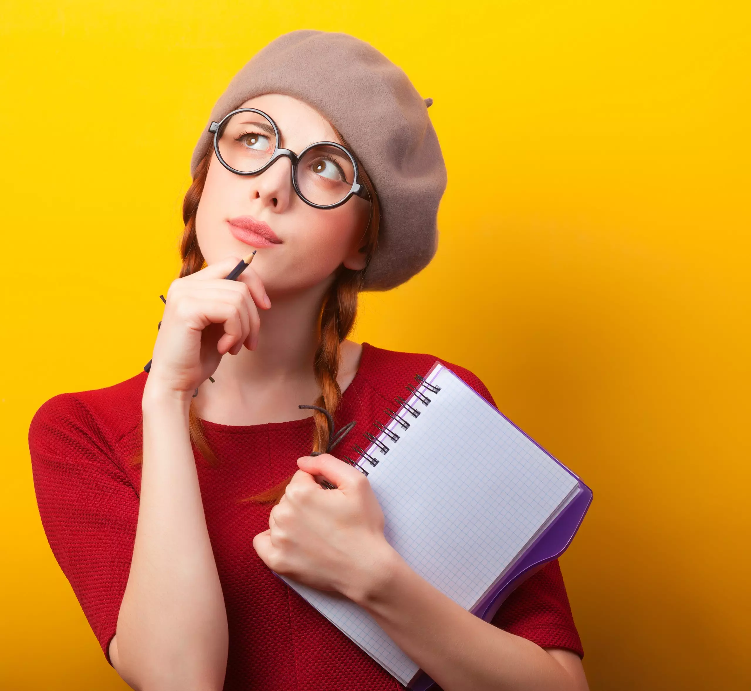 Woman thinking with notebook against yellow background.