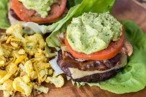 Burger with avocado, cheese, tomato, bacon, and seasoned cauliflower.