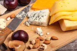 Assorted cheese platter with nuts and fruit.