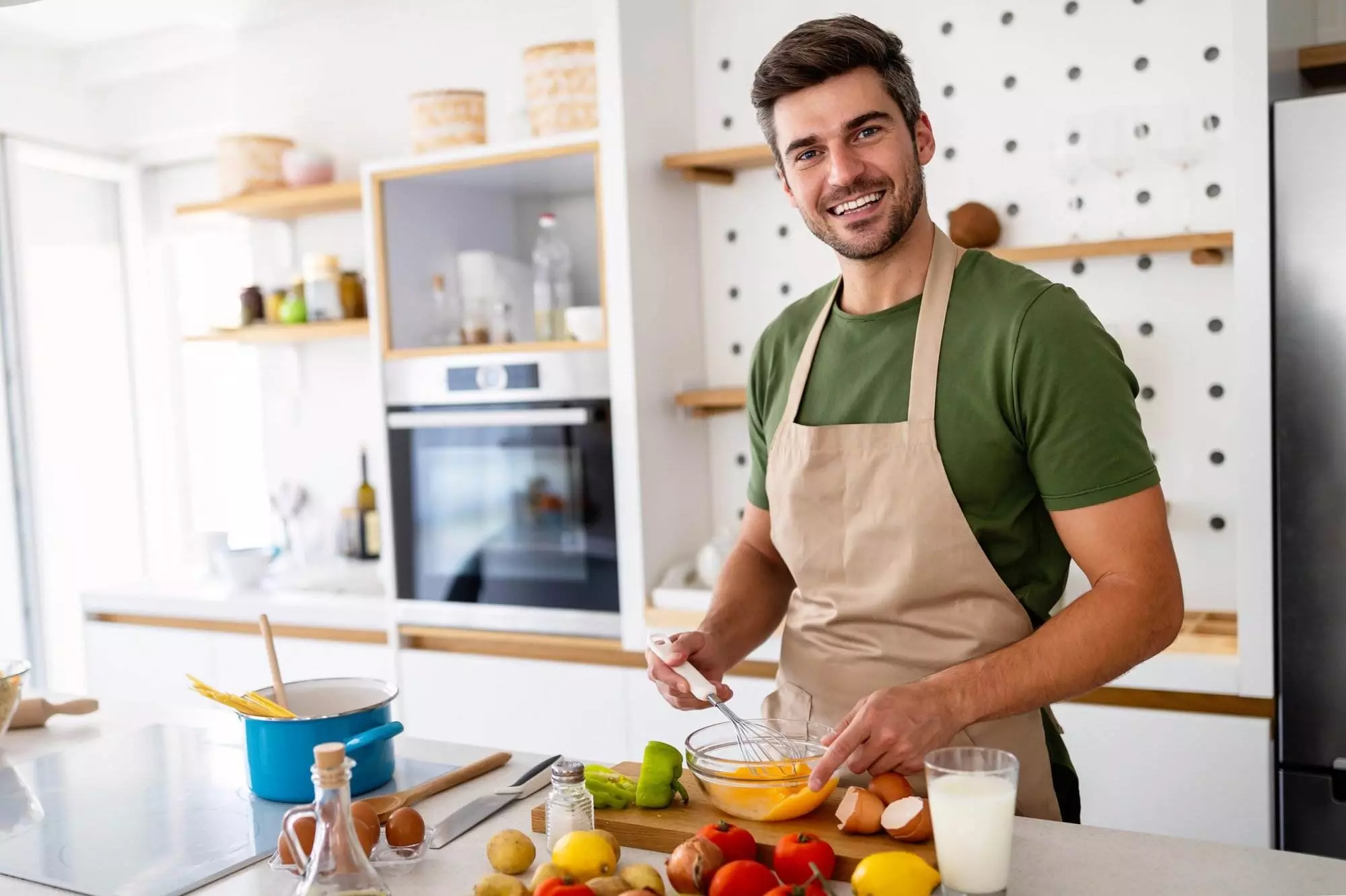 Man smiling while cooking in modern kitchen.