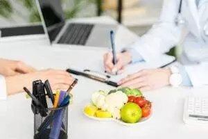 Nutritionist  consultation with fresh vegetables on desk.