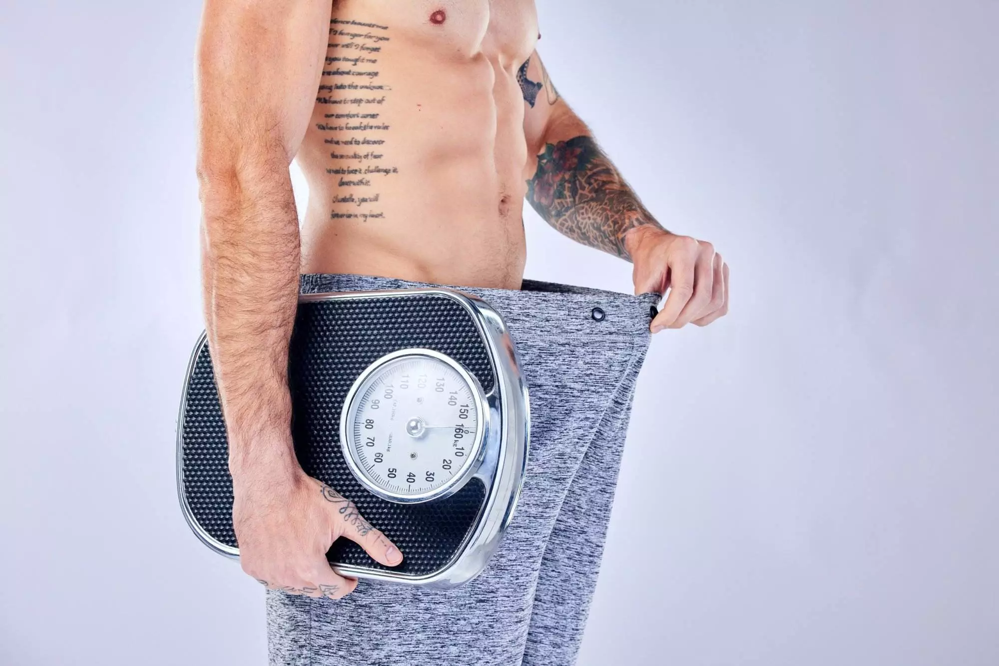 Man holding scale, showing weight loss achievement.