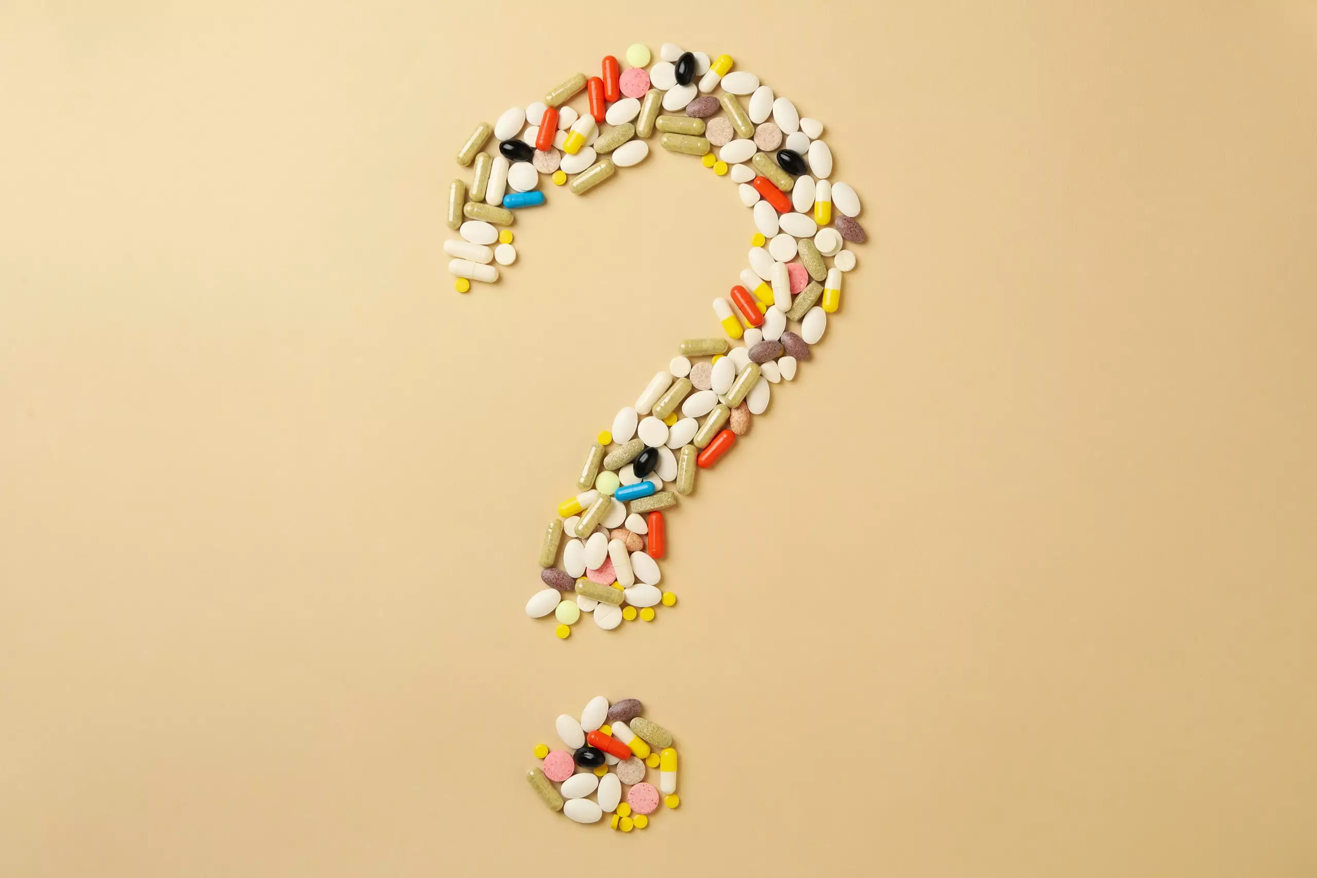 Question mark made of pills on beige background. Keto supplements concept.