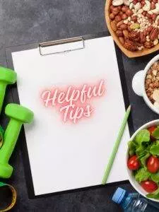 Clipboard with words Helpful Tips amongst healthy food and dumb bells. Healthy lifestyle.