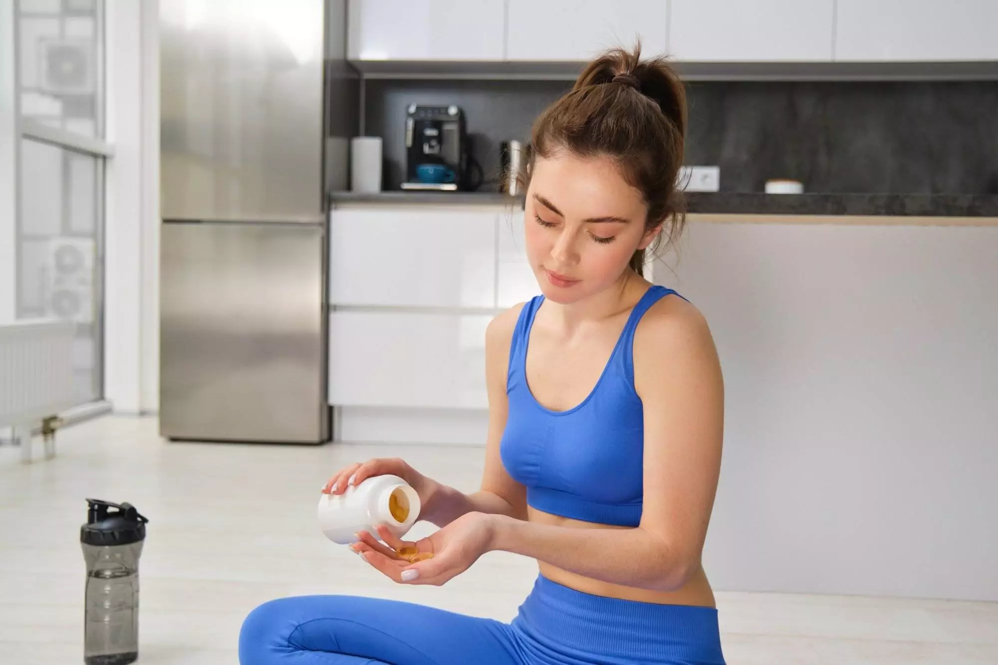 Woman taking vitamins in kitchen after workout