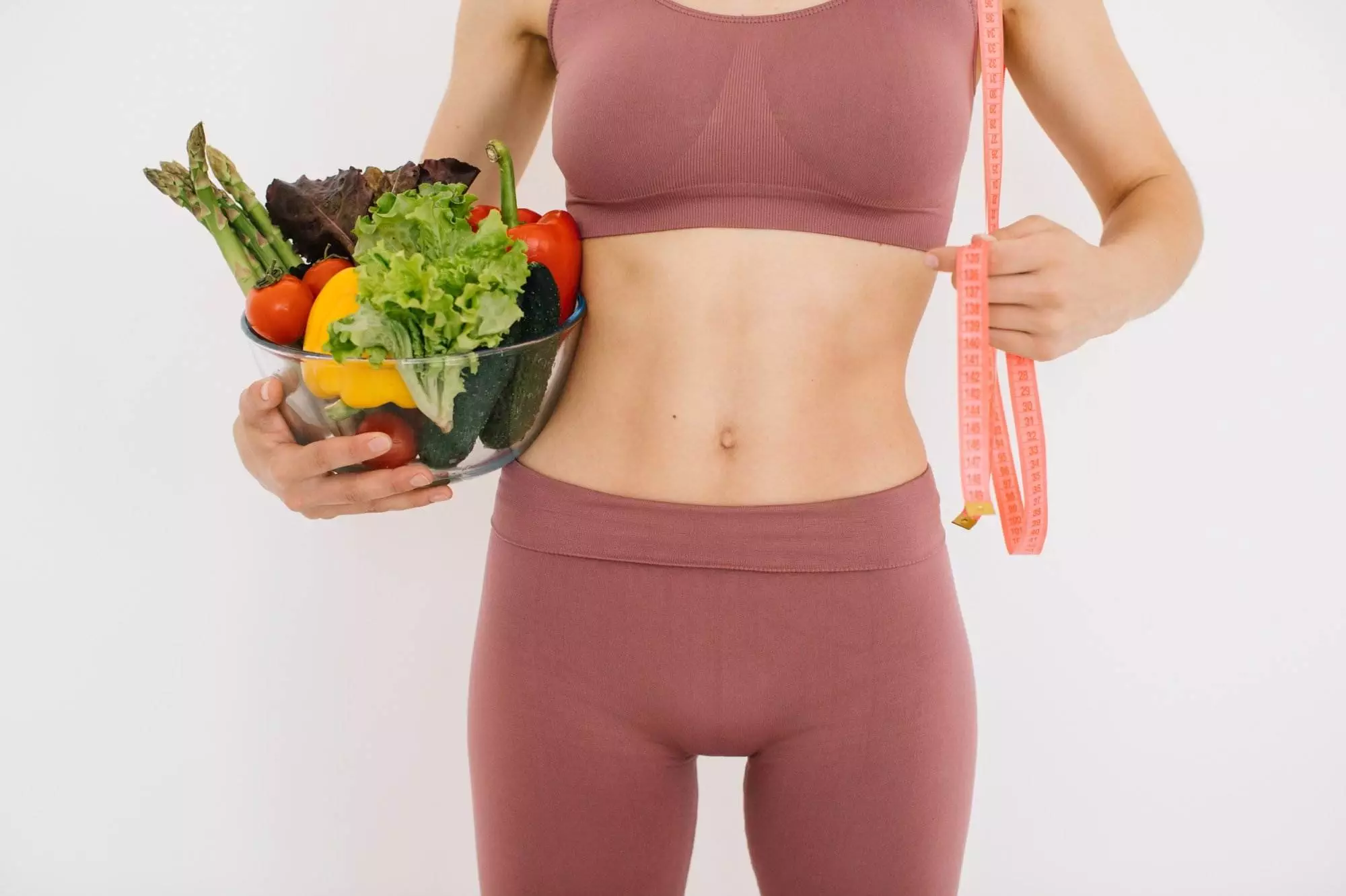 Woman holding vegetables, measuring waist fitness concept