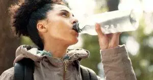 Woman drinking water from bottle outdoors