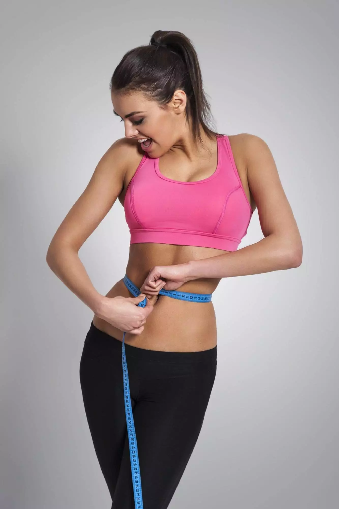Fit woman with measuring tape around waist