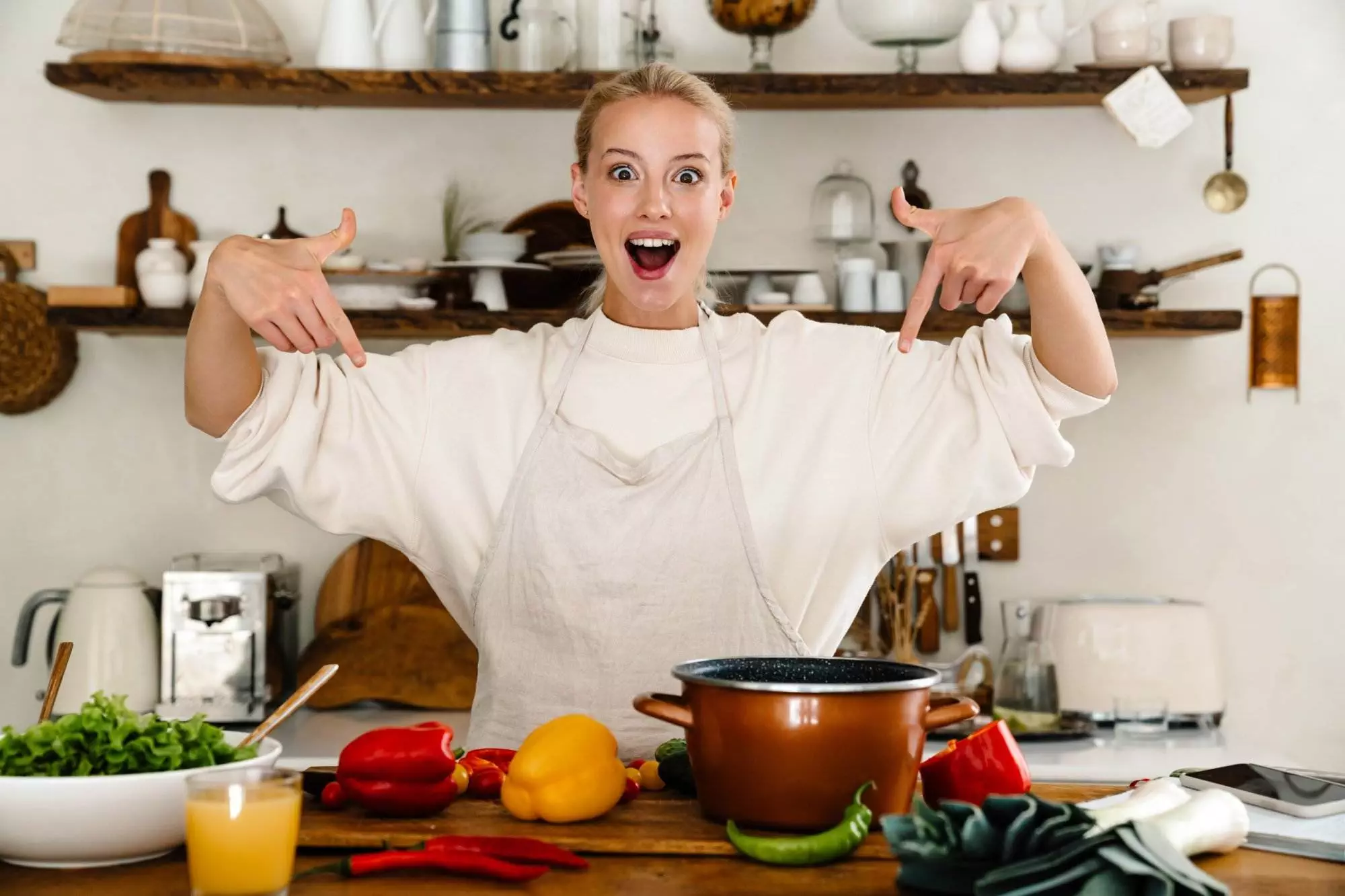 Excited woman cooking with colorful vegetables in kitchen.