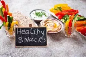Assorted vegetables with hummus; Healthy Snacks quoted on blackboard sign.