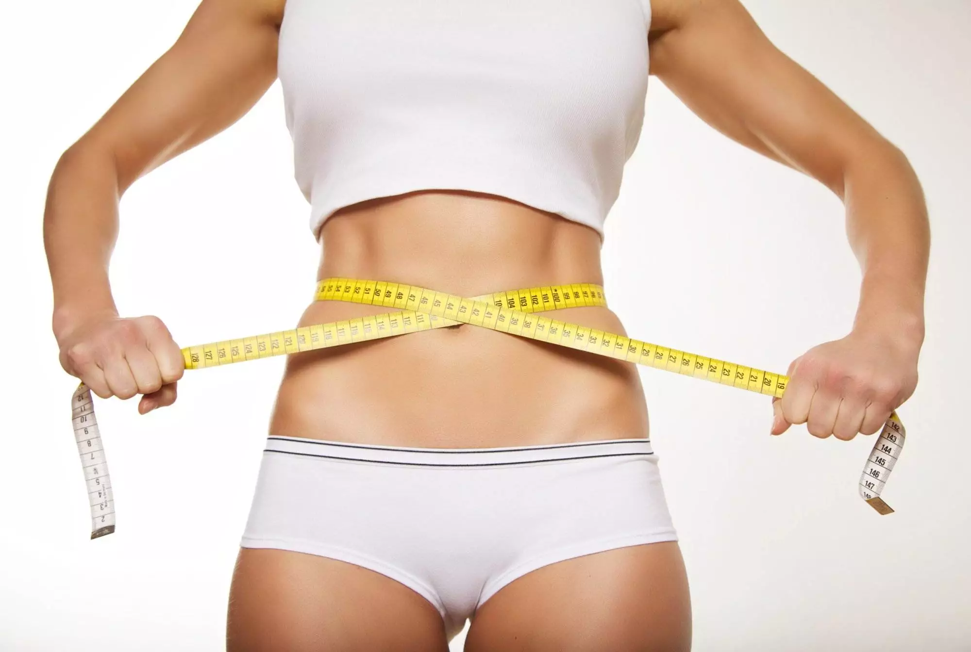Fit beautiful woman holding measure tape around her stomach. Weight loss concept.