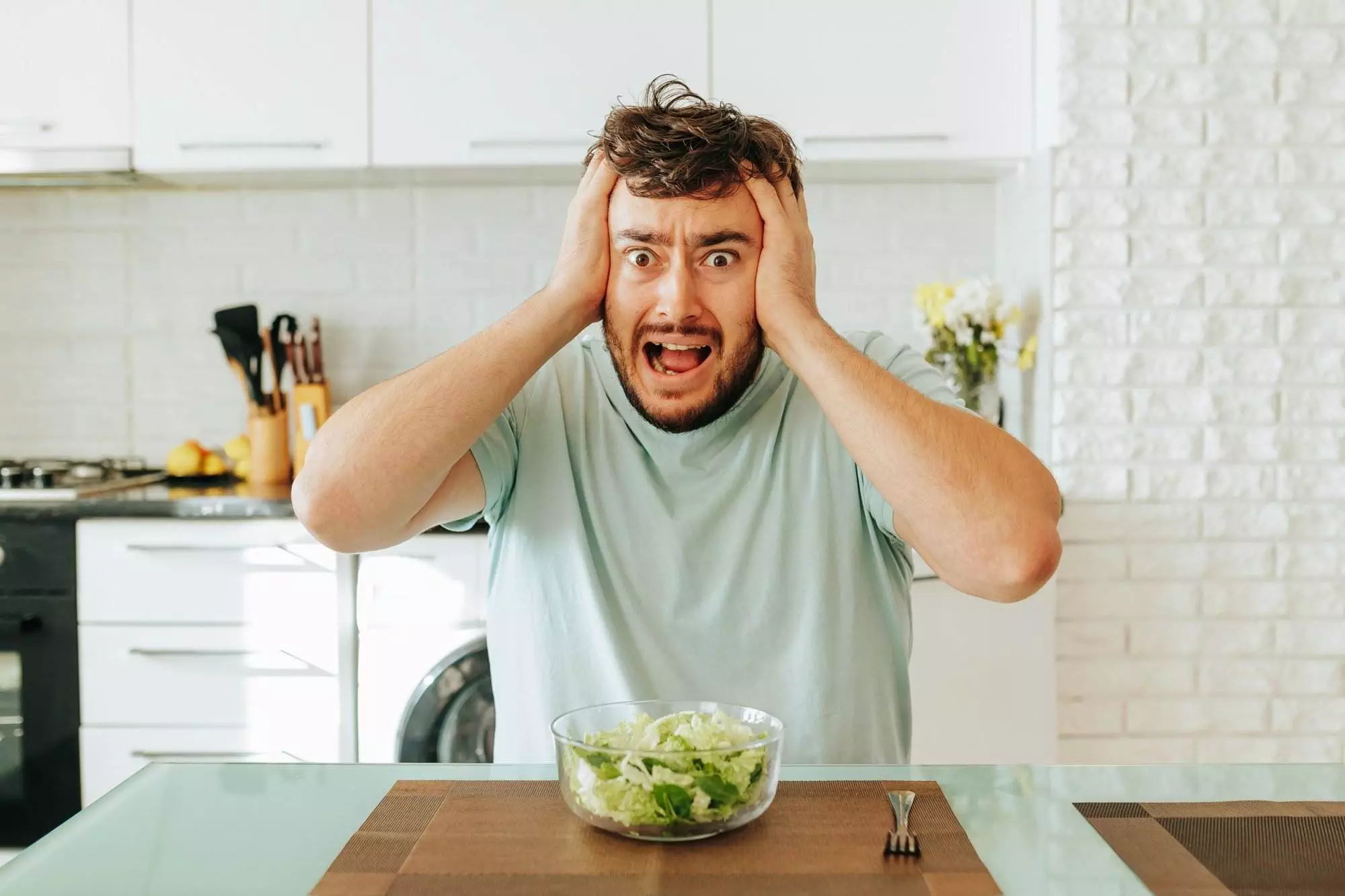 Man shocked by salad in modern kitchen. Keto lifestyle.
