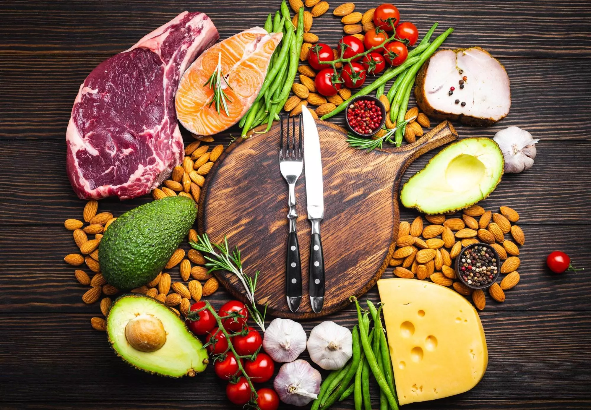 Assorted healthy food ingredients: meat, fish, cheese, vegetables, nuts, avocado on wooden background