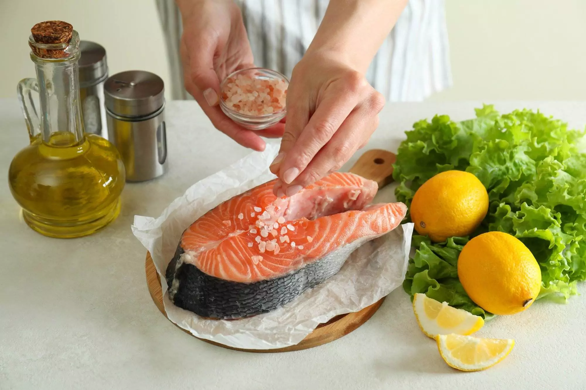 Seasoning fresh salmon with salt for cooking.