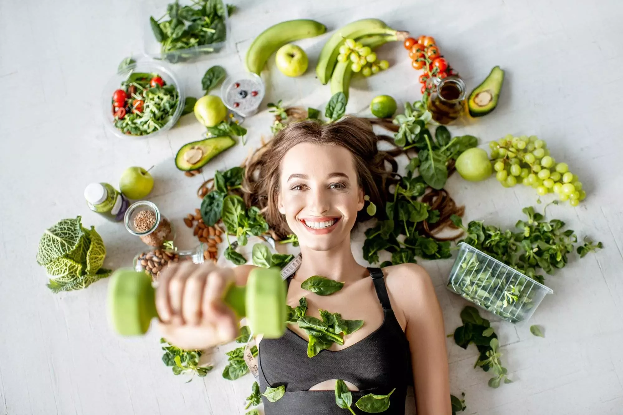 Woman with healthy food and dumbbells, fitness concept.