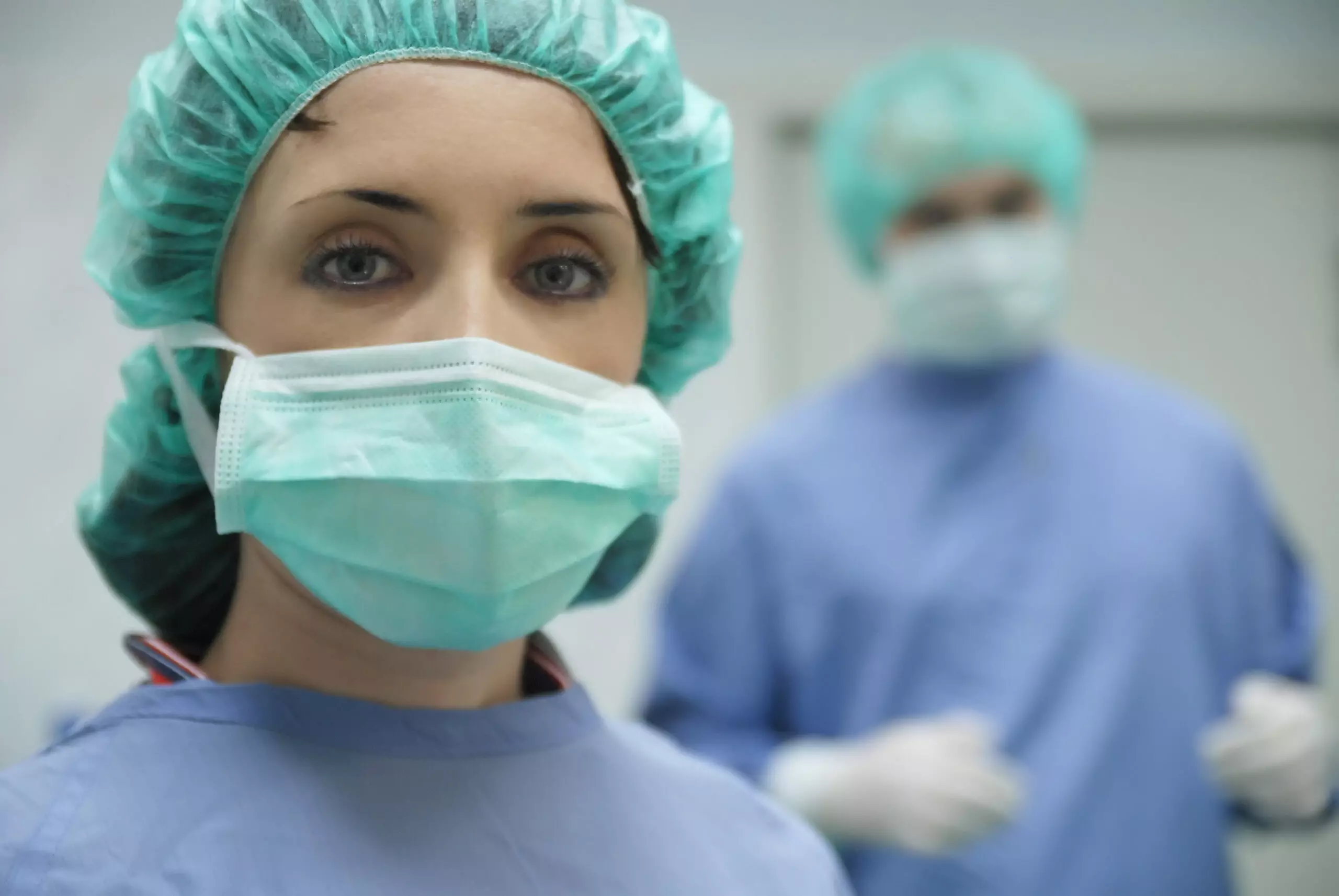 Medical professionals in surgery attire with masks.