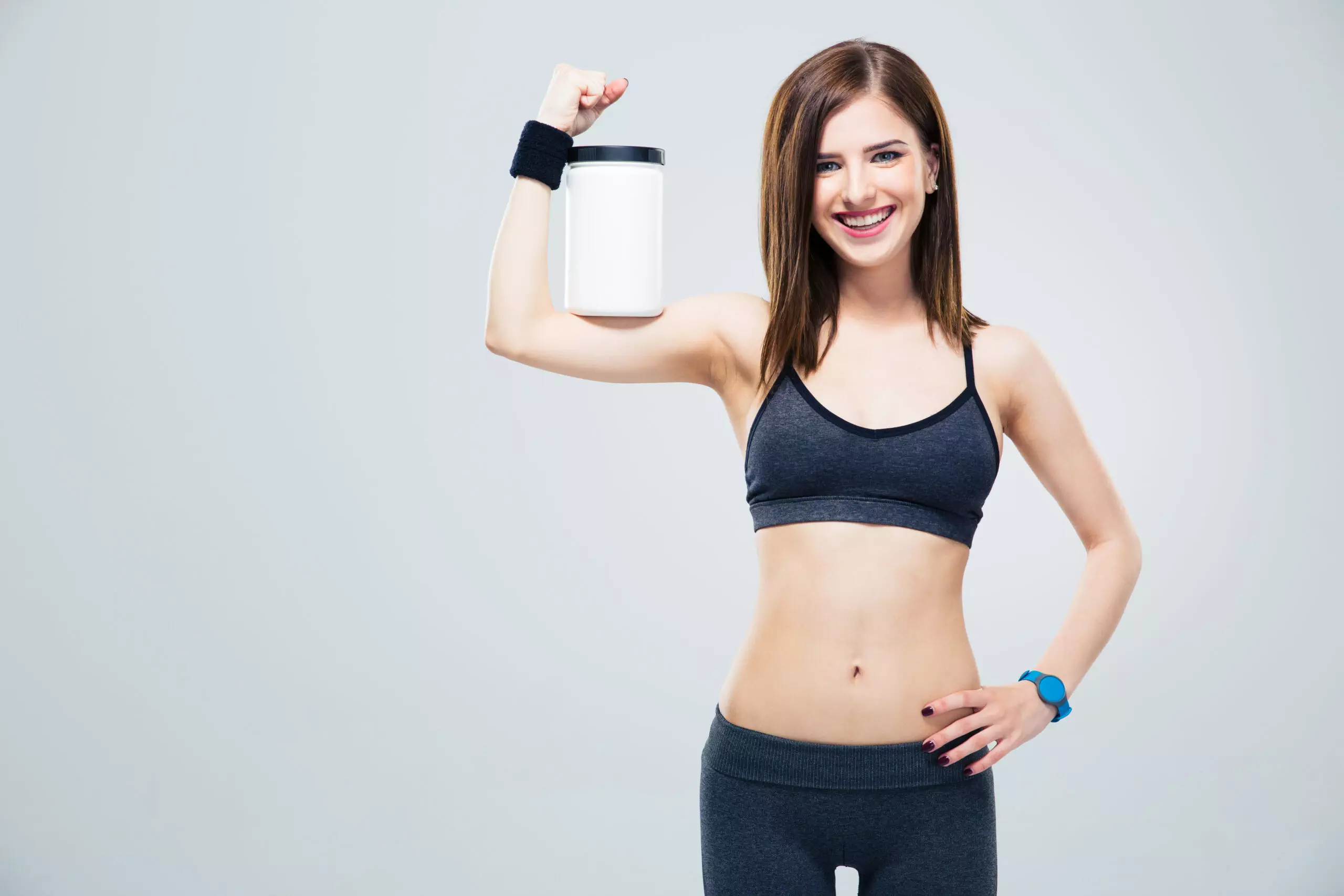 Woman holding protein jar, fitness attire
