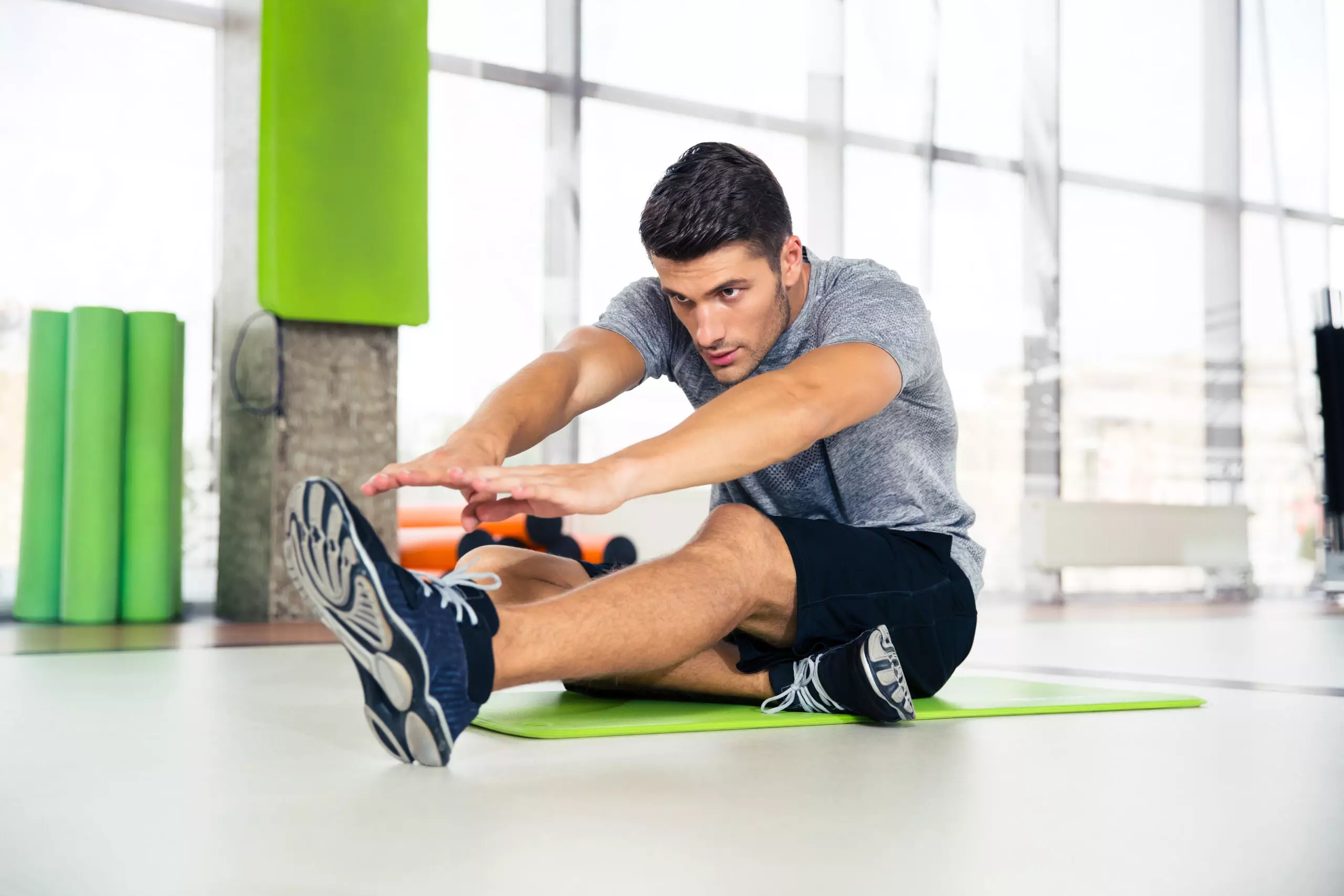 Man stretching on a gym mat indoors