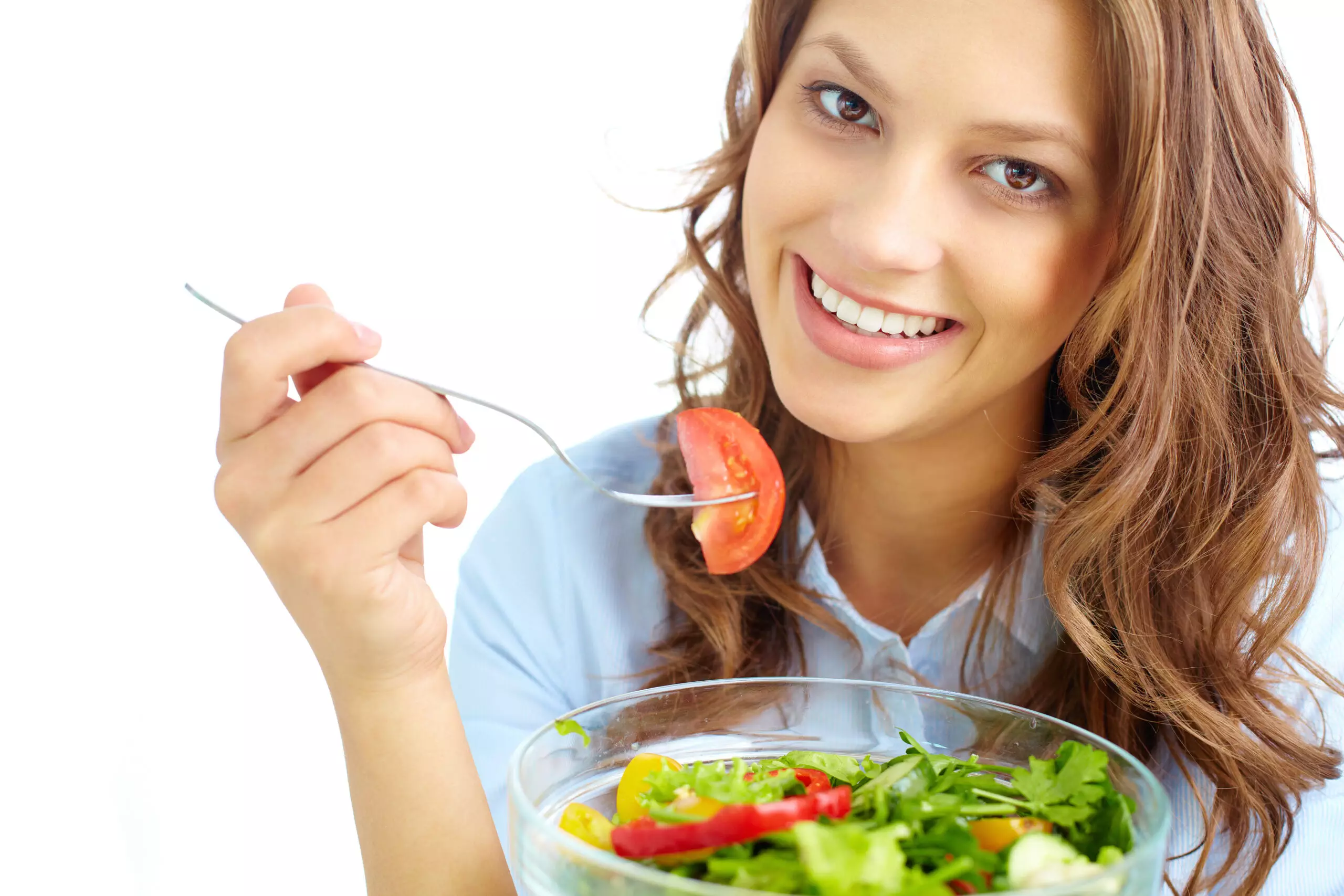 Woman smiling eating fresh salad with tomato.